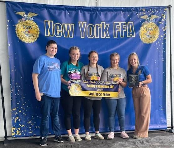 A group of high school students smile holding a banner that says "New York FFA State Finals Poultry Evaluation CDS 2023 3rd Place Team."